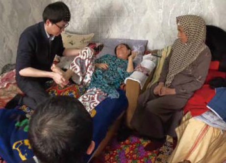 ウズベキスタン共和国にて、患者の自宅を訪問し、生活場面に おけるリハビリテーションを実演する車井寄附講座助教(左)
